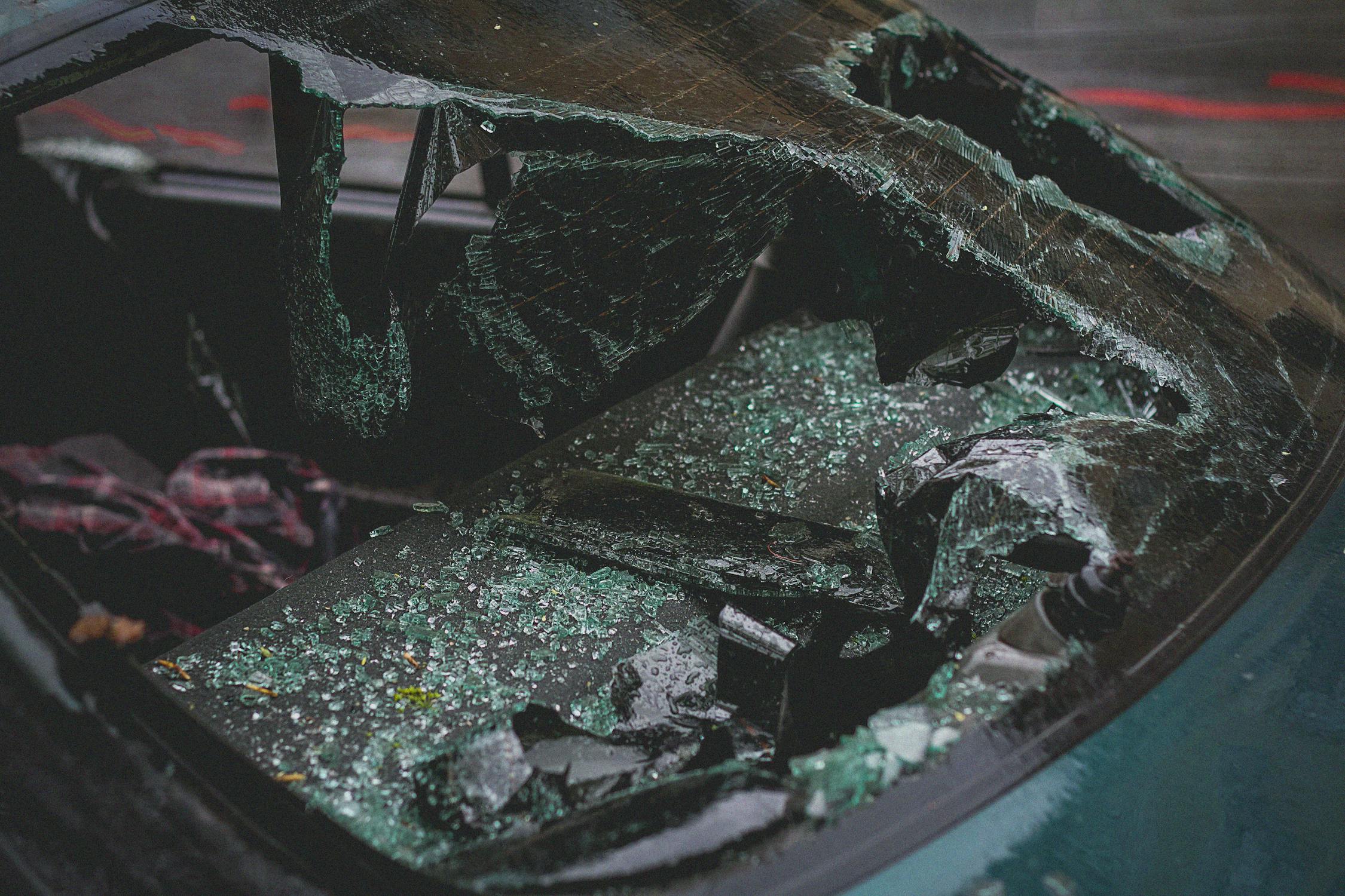 Shattered windshield and broken glass inside a severely damaged car after an accident